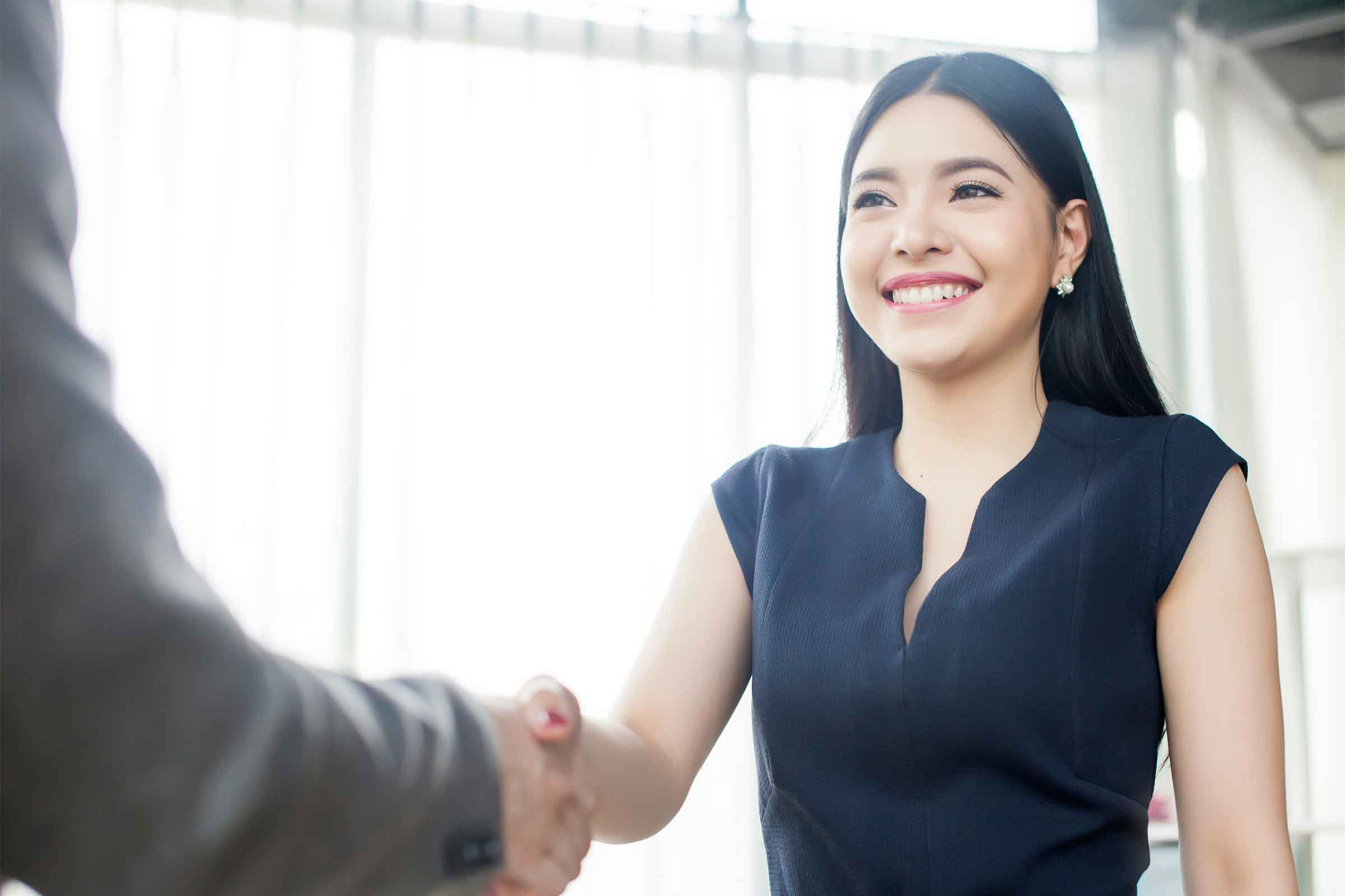 Picture of a smartly dressed business woman shaking hands confidently